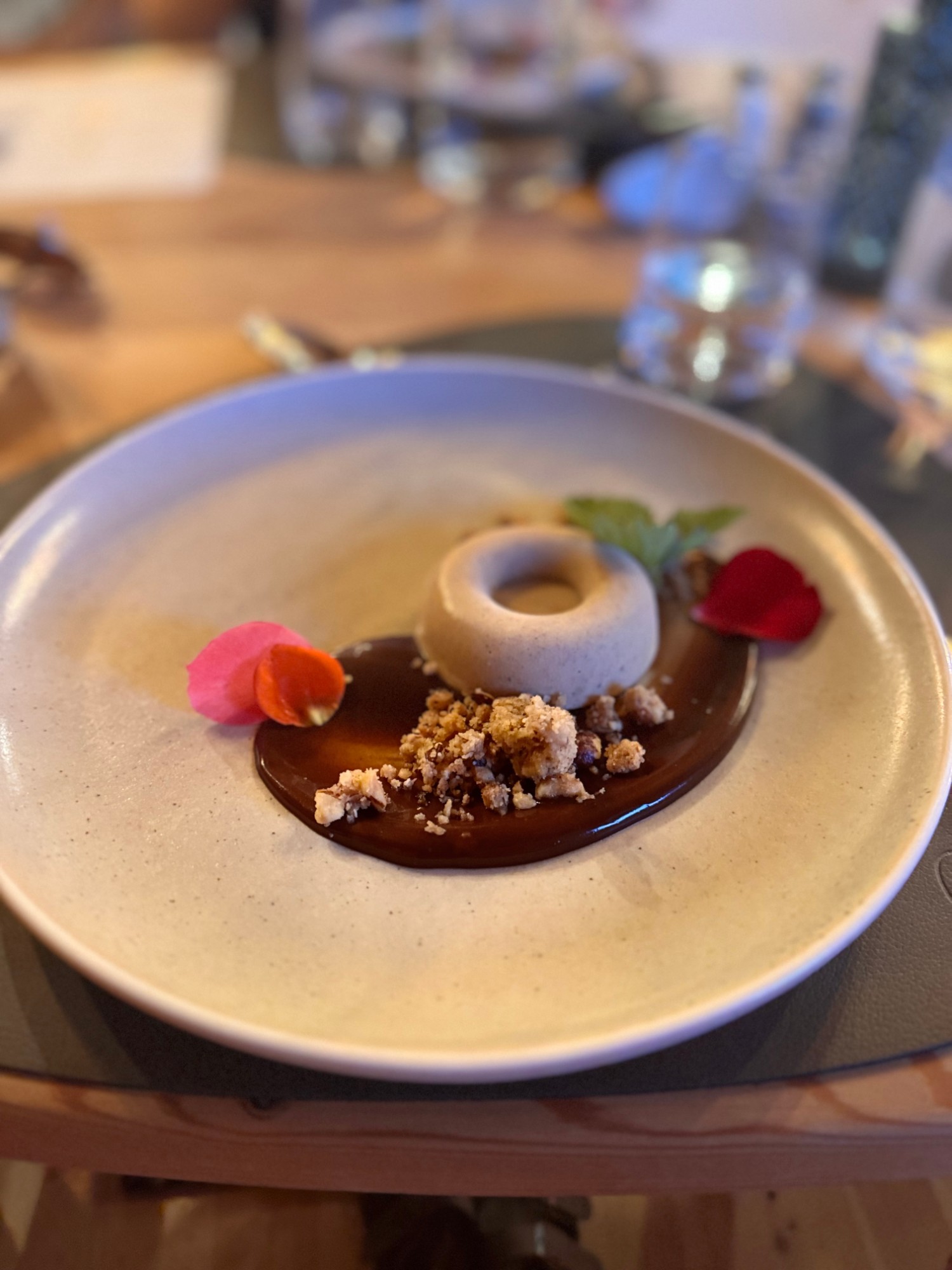 Pflanzenbasiertes Dessert mit Karamell und Blütenblättern, angerichtet auf hellem Teller