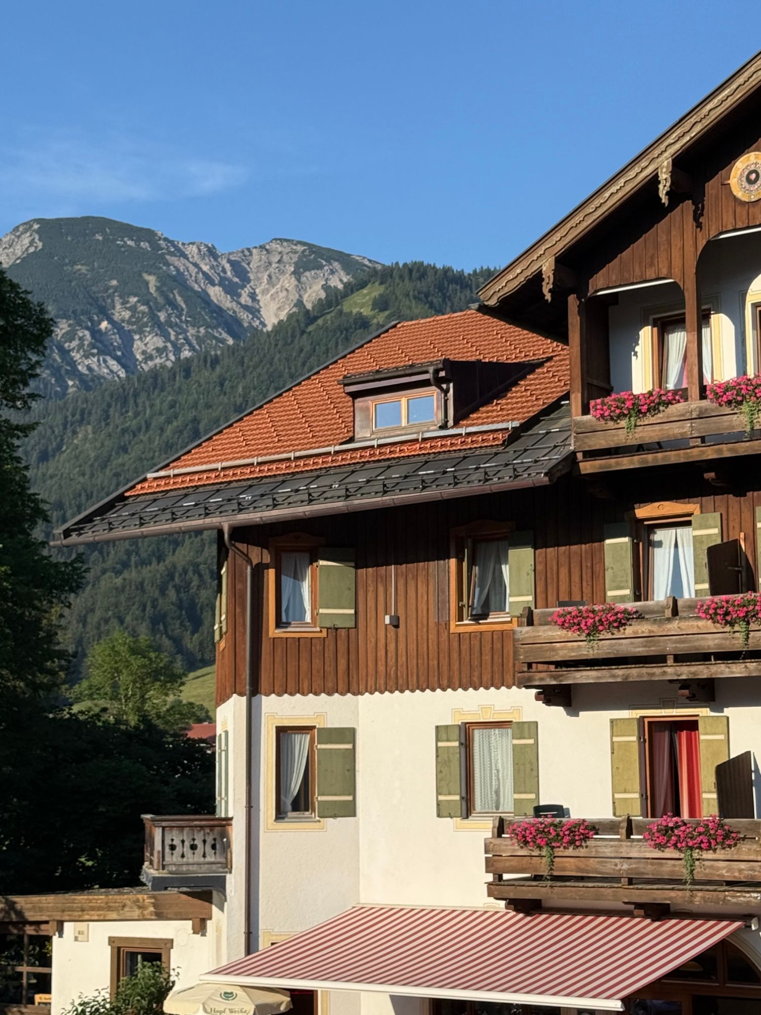 Alpenhotel mit Holzbalkonen und Blumenkästen vor Bergkulisse